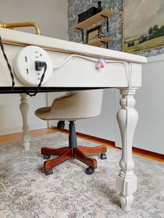 a desk with an electrical outlet plugged in to the top and underneath it, sitting on a carpeted floor