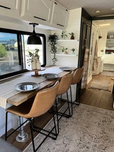 the dining table is set up in front of the kitchen and living room area, with large windows looking out onto the outdoors