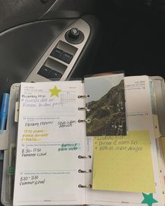 an open planner book sitting on top of a car dashboard