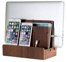 three cell phones in a wooden charging station