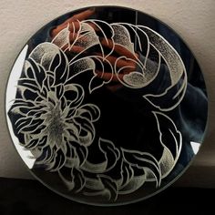 a decorative glass plate sitting on top of a wooden table next to a white wall