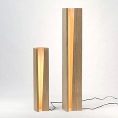 two tall wooden lamps sitting next to each other on a white surface with wires running through them