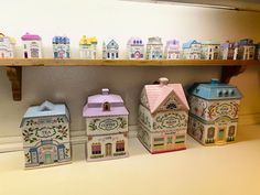 small ceramic houses are lined up on the shelf in front of a wall full of them