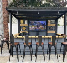 an outdoor bar with four chairs and a television