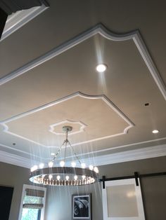 a chandelier hanging from the ceiling in a room with gray walls and white trim