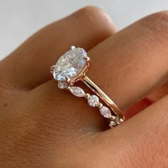 a woman's hand with a diamond ring on top of her finger and an engagement band