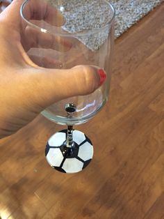 a hand holding a wine glass with a soccer ball on it