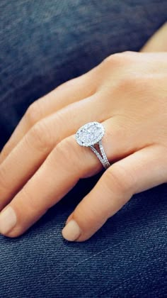 a close up of a person's hand with a diamond ring on their finger