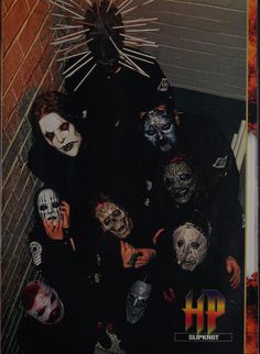 a group of people with masks on their faces and hands in front of a brick wall