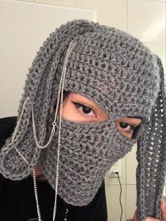 a woman wearing a crochet mask with chains on her head