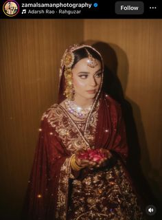 a woman in a red and gold bridal outfit holding a small item with lights on it