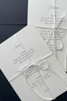 the wedding stationery is laid out on top of each other, and tied together with ribbon