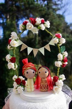 a wedding cake topper with two bride and groom figurines sitting on it