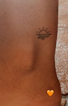 a small sun tattoo on the side of a woman's leg with an orange heart