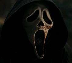 a person in a black hooded jacket with their mouth open and blood splattered on the face