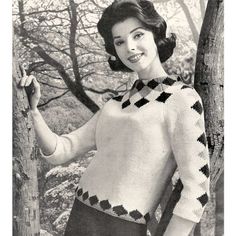 a woman standing next to a tree wearing a sweater with argyles on the sleeves