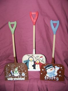 three snowman themed wooden utensils sitting on a pink sheet with the words frosty and frosty