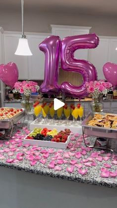 a table filled with lots of food and balloons in the shape of the number fifteen