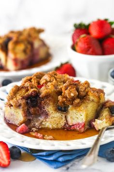 a slice of blueberry crumb coffee cake on a plate with strawberries in the background