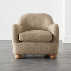 a beige chair sitting on top of a hard wood floor next to a white wall