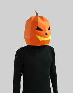 a person wearing an orange paper pumpkin mask on top of their head and black shirt