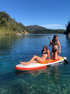 two women in bikinis paddling on a paddle board