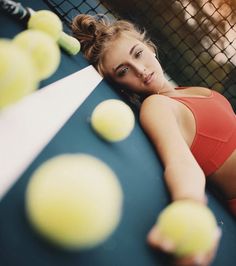 a woman laying on top of a tennis court holding a racquet and ball