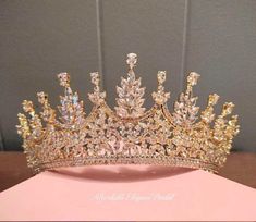 a gold tiara is sitting on top of a pink box