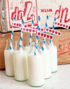 four glass bottles with blue and white straws in them