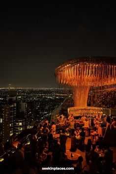 an aerial view of a city at night with people eating and drinking in the foreground