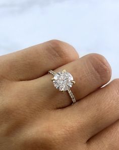 a woman's hand with a diamond ring on top of her finger and the other hand holding an engagement ring