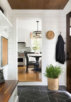 an entry way with a potted plant on the floor and a wooden table in the background