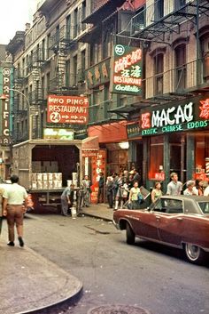 an old photo of people walking down the street in front of stores and buildings with neon signs