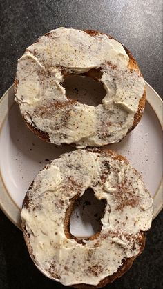 two donuts with white frosting sitting on a plate