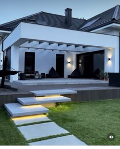 a white house with steps leading up to the front door and patio area at night