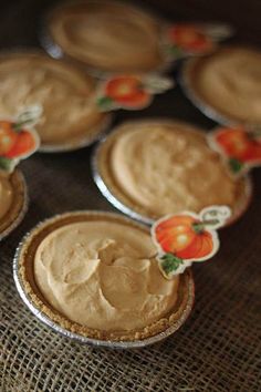 several pies with frosting sitting on top of a cloth covered tablecloth,