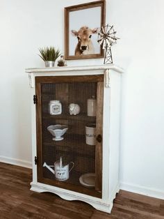 a white cabinet with glass doors and a cow's head mounted on the top