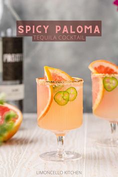 two glasses filled with alcohol and garnished with sliced oranges, cucumber and lime