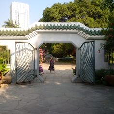 a woman is walking through an open gated area with potted plants on either side