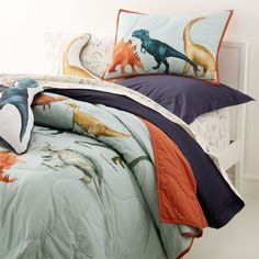 a bed with dinosaurs on it and two pillows