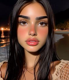 a woman with long black hair and brown eyes is standing on the beach at night