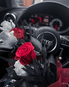 a bouquet of flowers sitting on the dashboard of a car with steering wheel controls in the background