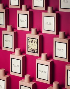 a wall covered in pink and white bottles with black frames on it's sides