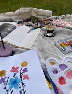 an open book sitting on top of a table covered in art supplies