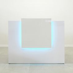 a white sculpture with blue lights on the sides and an empty wall in the background