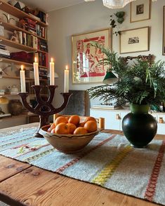 a bowl filled with oranges sitting on top of a table next to a vase