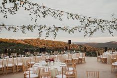 an outdoor venue with tables and chairs set up for a wedding reception in the mountains