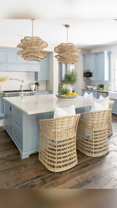 a large kitchen with blue cabinets and wicker baskets on the countertop, along with two stools