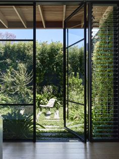 an open room with glass walls and plants on the outside, looking out onto a garden