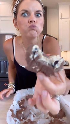 a woman holding a butterfly in her hand while sitting at a table with food on it